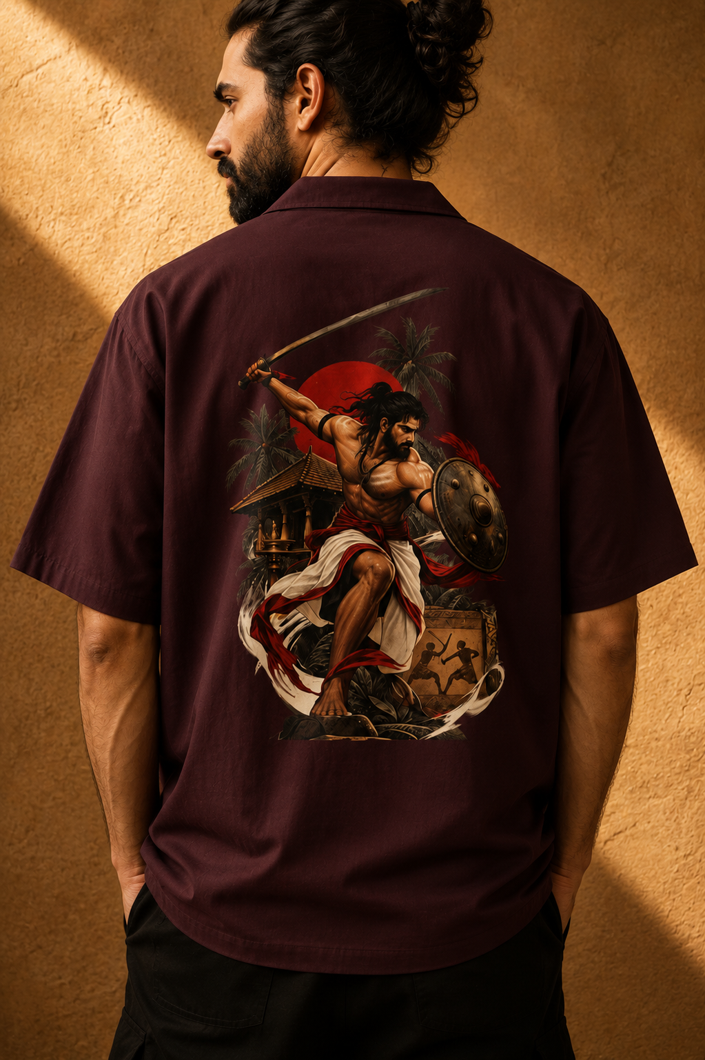 A man shown from behind wearing a short-sleeve burgundy button-up shirt with a large, detailed graphic print of a warrior on the back, set against a textured warm brown wall.